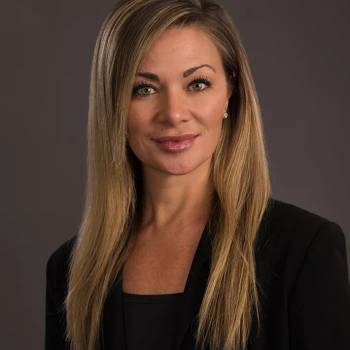 Douglas S Harrington MD vilkintis juodą smokingą ir varlytę, stovi priešais banerį su logotipais, įskaitant Oscars ir HeartDaHeart Foundation, oficiali renginio aplinka, neutralus ir profesionalus įspūdis, matomas tekstas: Oscars HeartDaHeart Foundation UnmaskHeartDisease