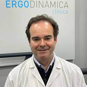 Douglas S Harrington MD vilkintis juodą smokingą ir varlytę, stovi priešais banerį su logotipais, įskaitant Oscars ir HeartDaHeart Foundation, oficiali renginio aplinka, neutralus ir profesionalus įspūdis, matomas tekstas: Oscars HeartDaHeart Foundation UnmaskHeartDisease